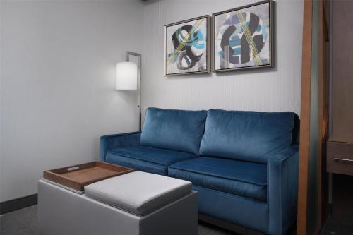a living room with a blue couch and a stool at Best Western Premier Hotel at Fisher's Landing in Vancouver