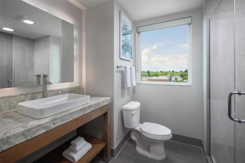 a bathroom with a sink and a toilet and a window at Best Western Premier Hotel at Fisher's Landing in Vancouver