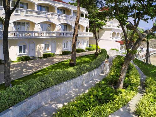 头顿Mercure Vung Tau Resort的一座白色的大楼，前面有树