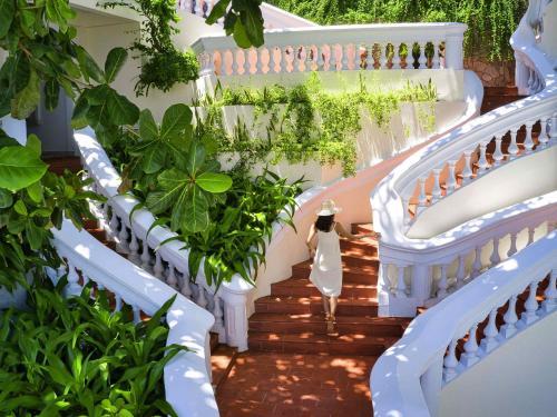 头顿Mercure Vung Tau Resort的穿着白色衣服的女人走下楼梯