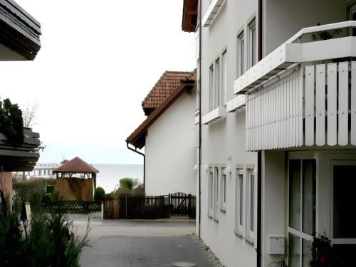 an alley between two white buildings with the ocean in the background at Sommerhof Rauber in Immenstaad am Bodensee