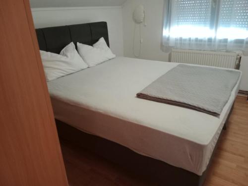 a bed with white sheets and pillows in a room at Apartman Bojan in Prnjavor