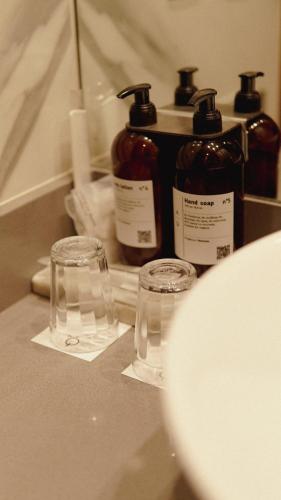 two bottles and glasses sitting on a bathroom counter at AQ Tailored Suites in Buenos Aires