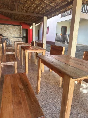 a row of wooden tables and chairs in a restaurant at Pousada Rio Cipó in Serra do Cipo
