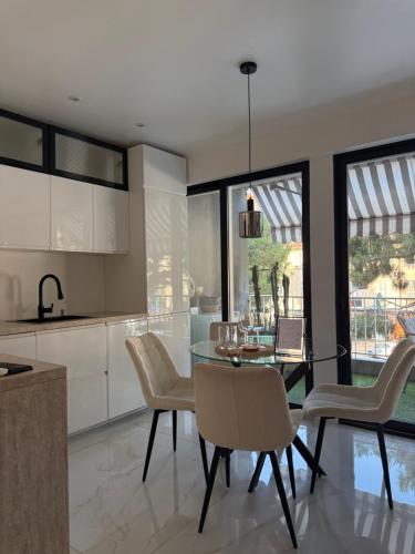 une cuisine et une salle à manger avec une table et des chaises en verre dans l'établissement Le Soleil Tropezien, Somptueux 2 pièces rénové, Terrasse, Centre, Vue Mer, Menton, à Menton