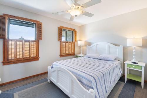 a white bedroom with a bed and two windows at Endless Summer in Sanderling