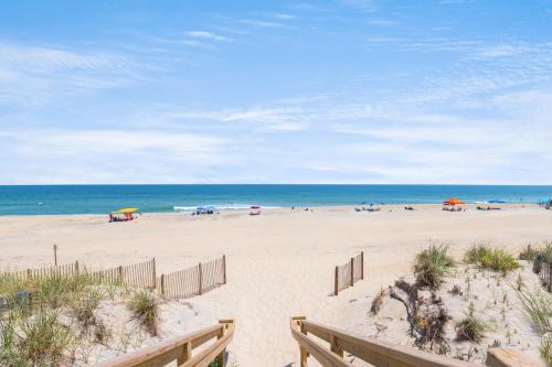 a beach with people and umbrellas and the ocean at Endless Summer in Sanderling