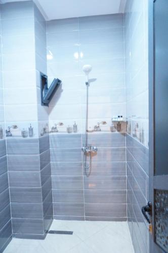 a bathroom with a shower with gray tiles at 2 Voies Résidence in Dakhla