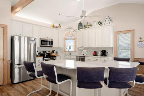 a kitchen with white cabinets and a large island with chairs at Fergusons Flagship in Nags Head