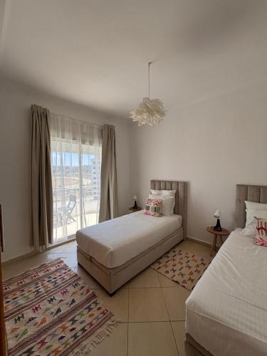 a bedroom with two beds and a window at Sublime T3 bord de mer avec piscine & Balcon I Proche Aéroport in Hajreien