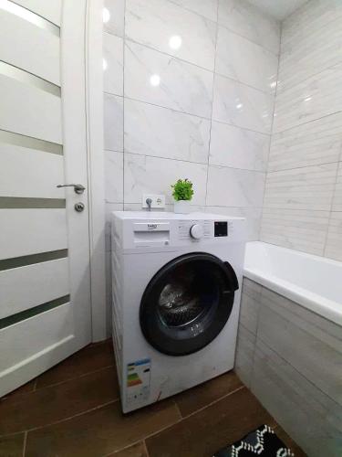 a washing machine in a bathroom next to a tub at Апартаменты Marin в самом центре in Kharkiv