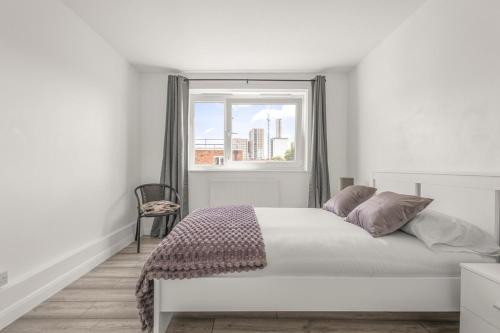 バーキングにあるBright & Modern London Apartmentのベッドと窓のある白い寝室