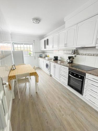 a kitchen with white cabinets and a table in it at GoldMar Beach Apartments - Praia da Vieira in Vieira de Leiria