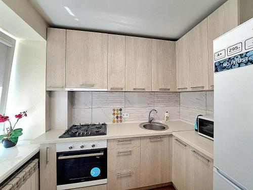 a kitchen with wooden cabinets and a sink and a stove at Апартаменты Marin в самом центре in Kharkiv