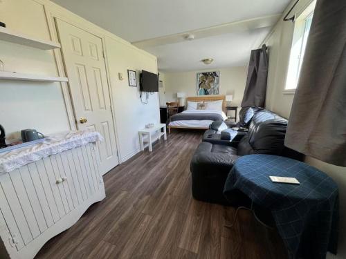 a living room with a black leather couch and a bedroom at Objectif Santé in Longueuil
