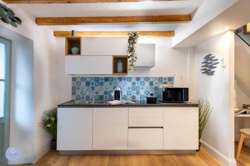 eine Küche mit weißen Schränken und blauen Fliesen in der Unterkunft Nido Blu - Vista Lago in Belgirate