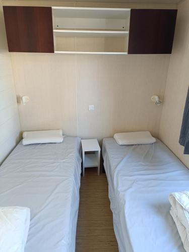 - 2 lits dans une petite chambre avec une petite table dans l'établissement Mobil home Vic la Gardiole, à Vic-la-Gardiole