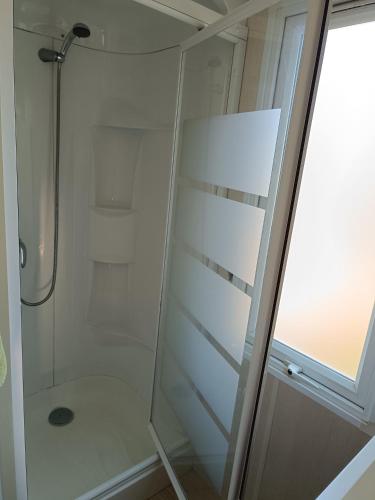 une douche avec une porte en verre à côté d'une fenêtre dans l'établissement Mobil home Vic la Gardiole, à Vic-la-Gardiole