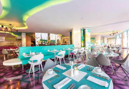a restaurant with white tables and chairs and a blue wall at Temptation Cancun Resort - All Inclusive - Adults Only in Cancún