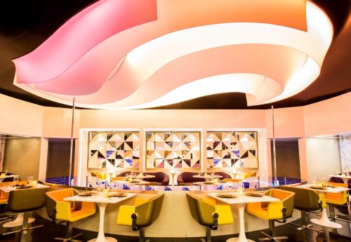 a dining room with tables and yellow chairs at Temptation Cancun Resort - All Inclusive - Adults Only in Cancún