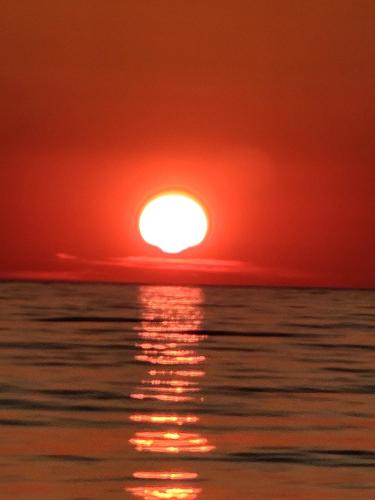 レジャにあるChill and Grillの空に太陽が輝く海に沈む夕日