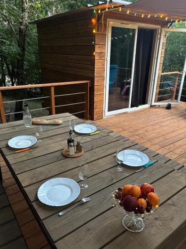 une table en bois avec des assiettes et des fruits sur une terrasse dans l'établissement Tiny house en pleine nature, à Arsac-en-Velay