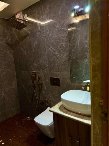 a bathroom with a sink and a toilet and a mirror at The Virasat Royale Penthouse in Patna