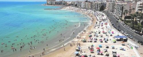 a crowd of people on a beach with umbrellas at Torrevieja Playa Cura in Torrevieja