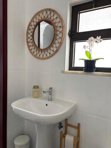 a bathroom with a sink and a mirror and a window at Casa Eça in Sesimbra