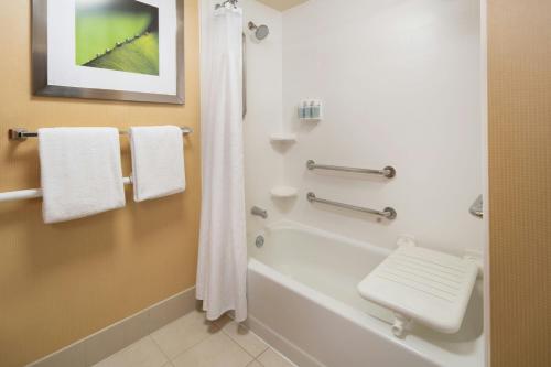 a bathroom with a tub and a shower with towels at Courtyard Irvine John Wayne Airport/Orange County in Irvine