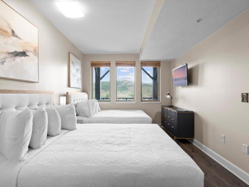 a white bedroom with two beds and a window at Crestview Condominiums by All Seasons Resort Lodging in Park City