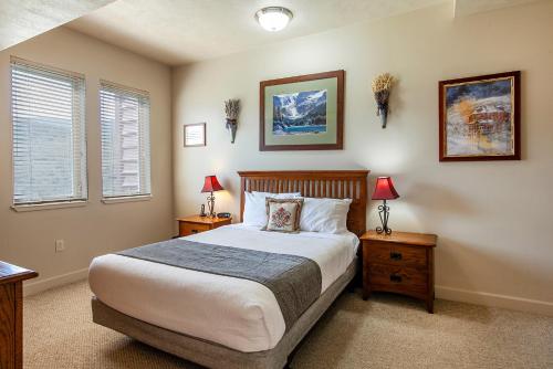 a bedroom with a bed with two night stands and two windows at Crestview Condominiums by All Seasons Resort Lodging in Park City