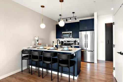 a kitchen with blue cabinets and a kitchen island with black chairs at W513 Cozy & Chic 1Bd In Downtown Minneapolis, Minutes From Minneapolis Convention Center & US Bank Arena in Minneapolis