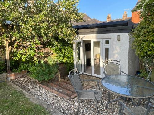 Un patio con una mesa y sillas frente a una casa. en Cosy, Cute Annnex, en Sidmouth