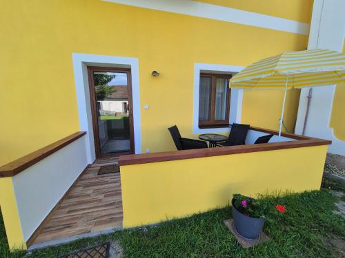 a yellow house with a deck with a table and an umbrella at Panská in Chlum u Třeboně