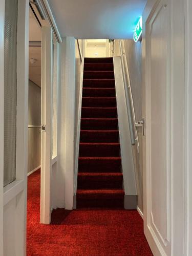 a hallway with a staircase with red carpet and a sign at Facade Hotel Amsterdam in Amsterdam