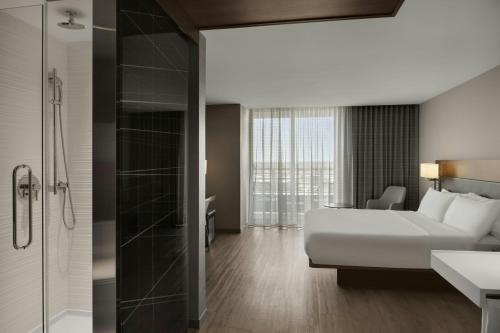 a hotel room with a bed and a shower at AC Hotel Cincinnati at Liberty Center in West Chester