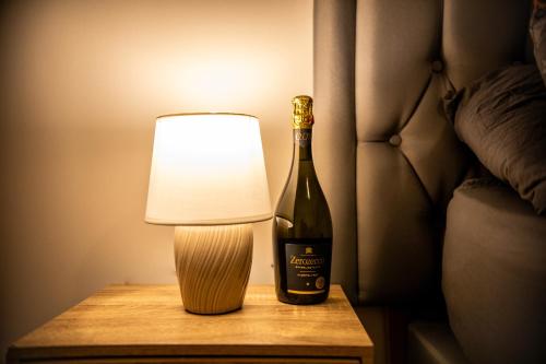 a bottle of wine and a lamp on a table at Stylish Kent apartment in Maidstone