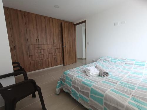 a bedroom with a bed and a chair and wooden cabinets at Brisa & Luz Paipa in Paipa