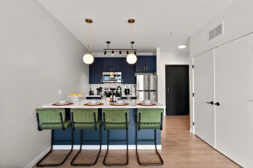 a kitchen with blue cabinets and a kitchen island with green chairs at W413 Stylish Luxury 1Bedroom In Downtown Minneapolis, Minutes From Minneapolis Convention Center & US Bank Arena in Minneapolis