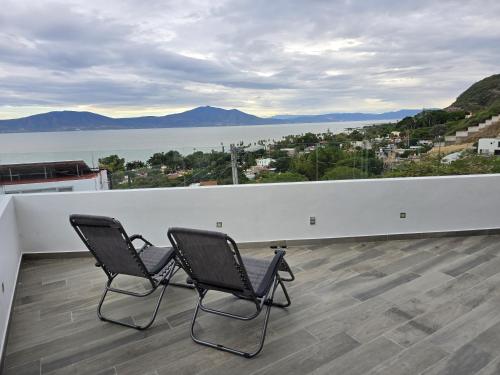 two chairs on a balcony with a view of the water at Casa de Alara in Chapala