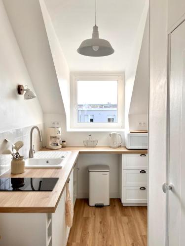 eine Küche mit Spüle und Fenster in der Unterkunft Le Petit Cottage - Appartement Centre-Ville & Plage in Concarneau