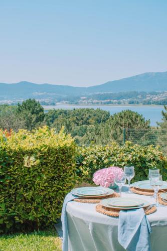 a table with plates and glasses and a view of the water at Just Like Home - Casa dos Pinheiros in Caminha
