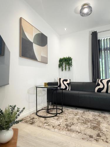 a living room with a black couch and a table at 'The Luxury Snug' - A Charming Modern Luxury 2-Bed Flat with Parkview - Free Parking in Northampton