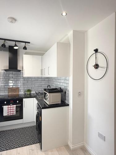 a kitchen with white cabinets and a microwave at 'The Luxury Snug' - A Charming Modern Luxury 2-Bed Flat with Parkview - Free Parking in Northampton