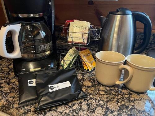 two cups on a counter next to a coffee maker at Serenity Escape Treehouse on 14 acres near Little River Canyon in Fort Payne