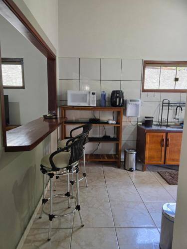 a kitchen with two chairs and a counter with a microwave at Casa Flor de Pitanga- Vila de São Jorge in Sao Jorge