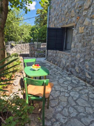 una mesa verde y sillas en un patio de piedra en House Bralići, en Stari Grad