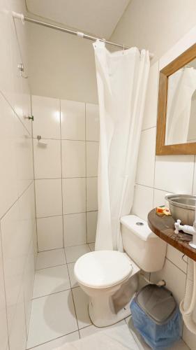 a white bathroom with a toilet and a shower at Che Brazil Pousada in Cruz