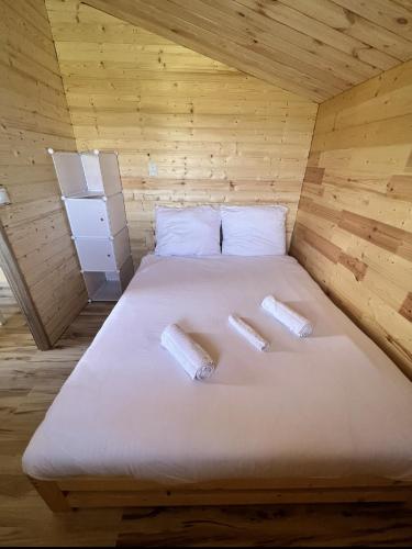 a bed in a wooden room with two pillows on it at Bałtycka Przystań Gąski - Domki z Basenem in Gąski